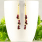 Long Gold Plated Chain and Garnet Crystal Chip Earrings displayed on a coffee mug.