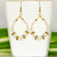 Clear Glass Crystal and Gold Hoop Earrings displayed on a tea cup.