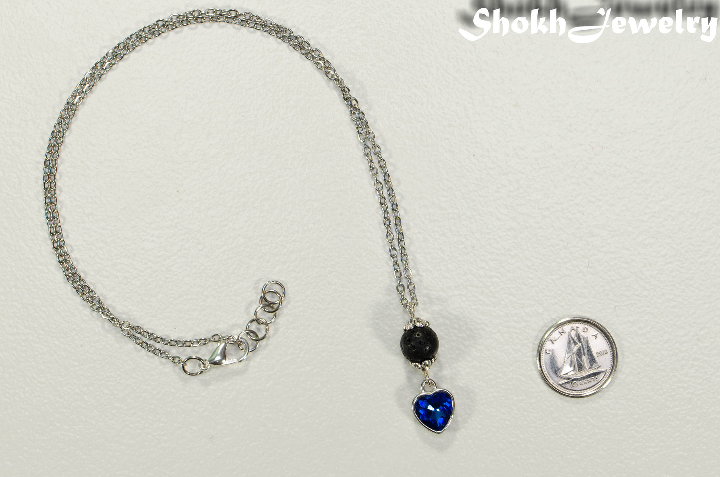 Lava Rock and Heart Shaped December Birthstone Choker Necklace beside a dime.