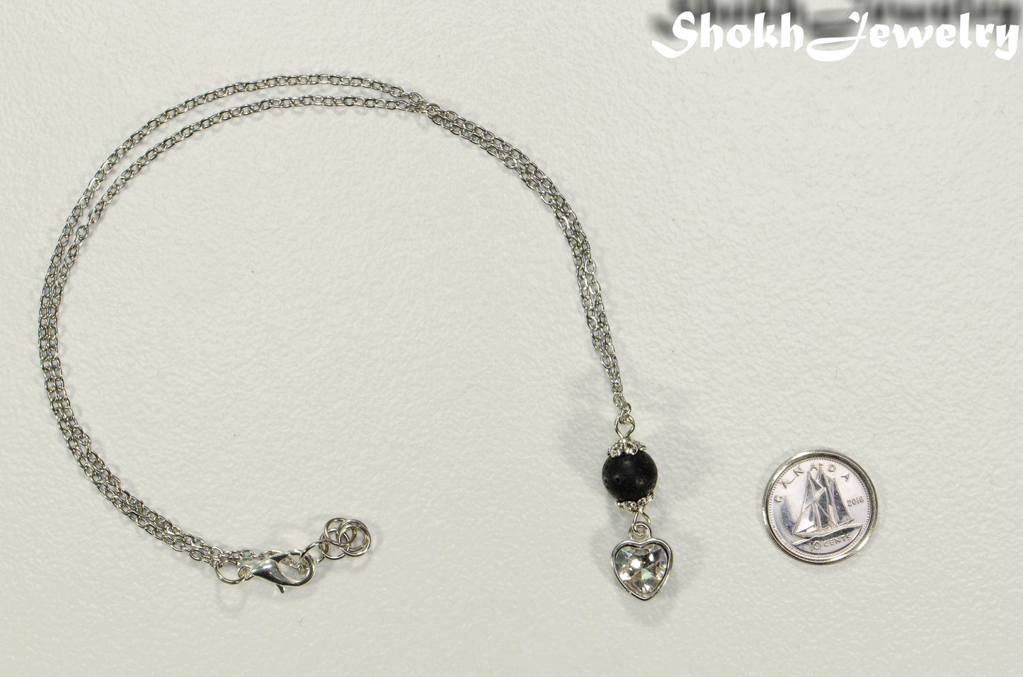 Lava Rock and Heart Shaped April Birthstone Choker Necklace beside a dime.