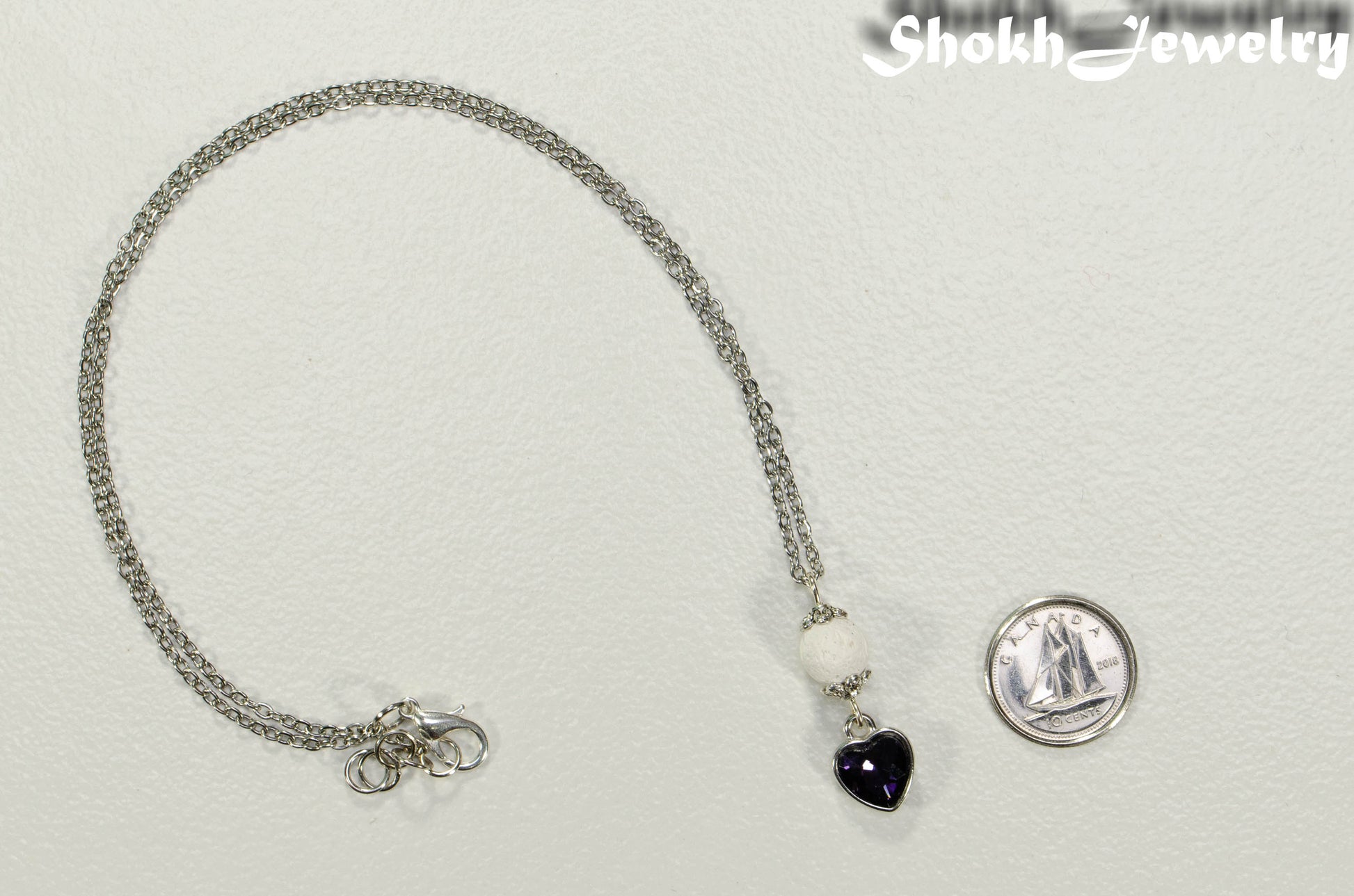 Lava Rock and Heart Shaped February Birthstone Choker Necklace beside a dime.