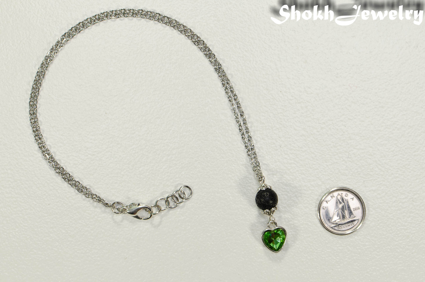 Lava Rock and Heart Shaped August Birthstone Choker Necklace beside a dime.