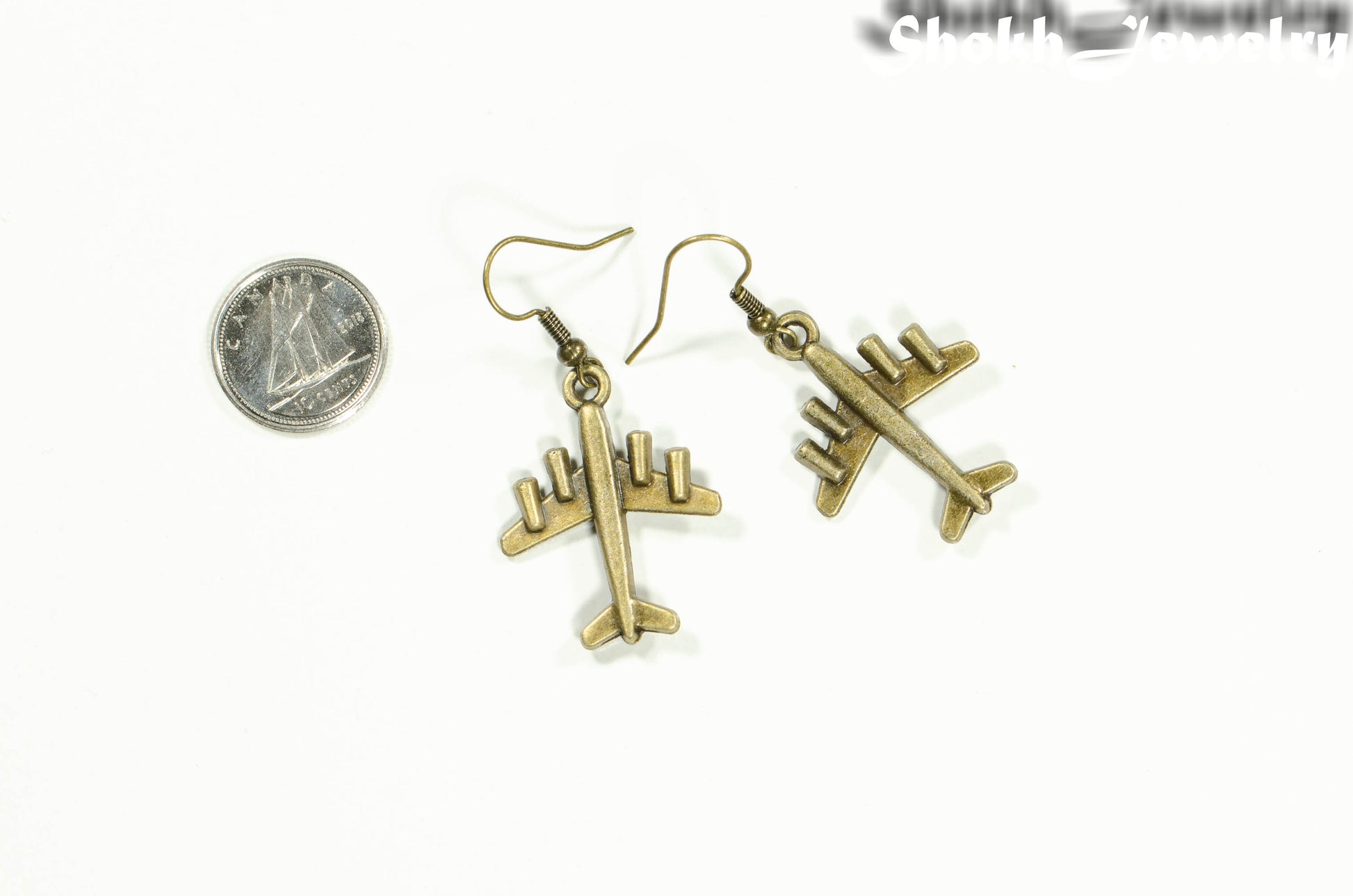 Antique Bronze 3D Plane Charm Earrings beside a dime.