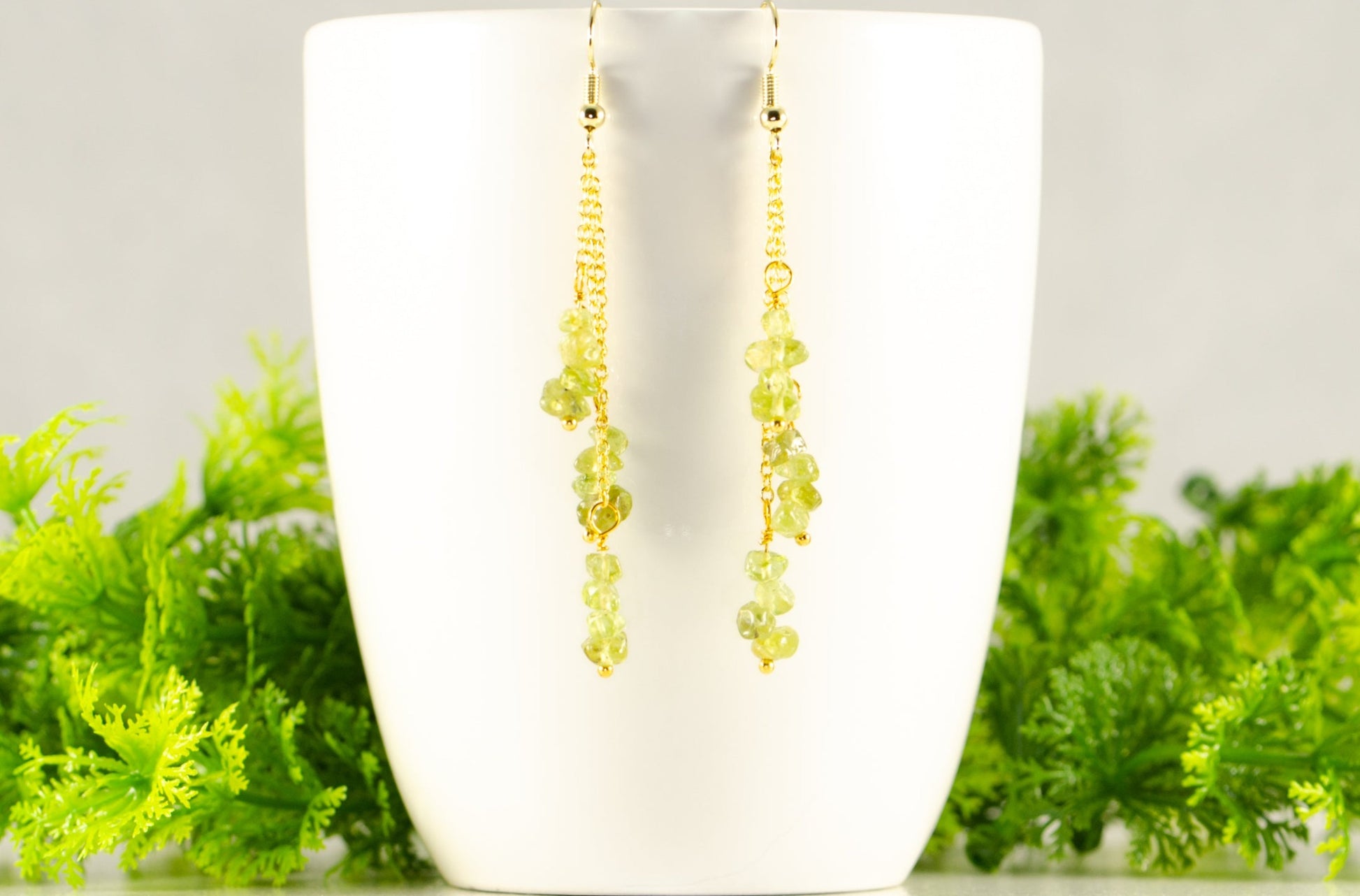 Long Gold Plated Chain and Peridot Chip Earrings displayed on a coffee mug.