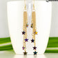 Extra Long Rainbow Hematite Star Earrings displayed on a coffee mug.