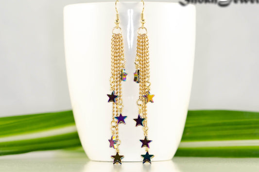 Extra Long Rainbow Hematite Star Earrings displayed on a coffee mug.