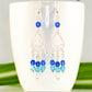 Ombre Blue Glass Crystal Chandelier Earrings displayed on a coffee mug.