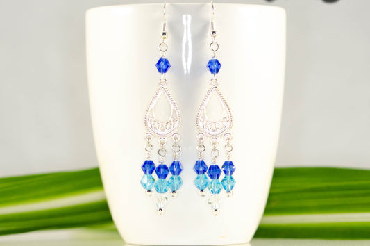Ombre Blue Glass Crystal Chandelier Earrings displayed on a coffee mug.