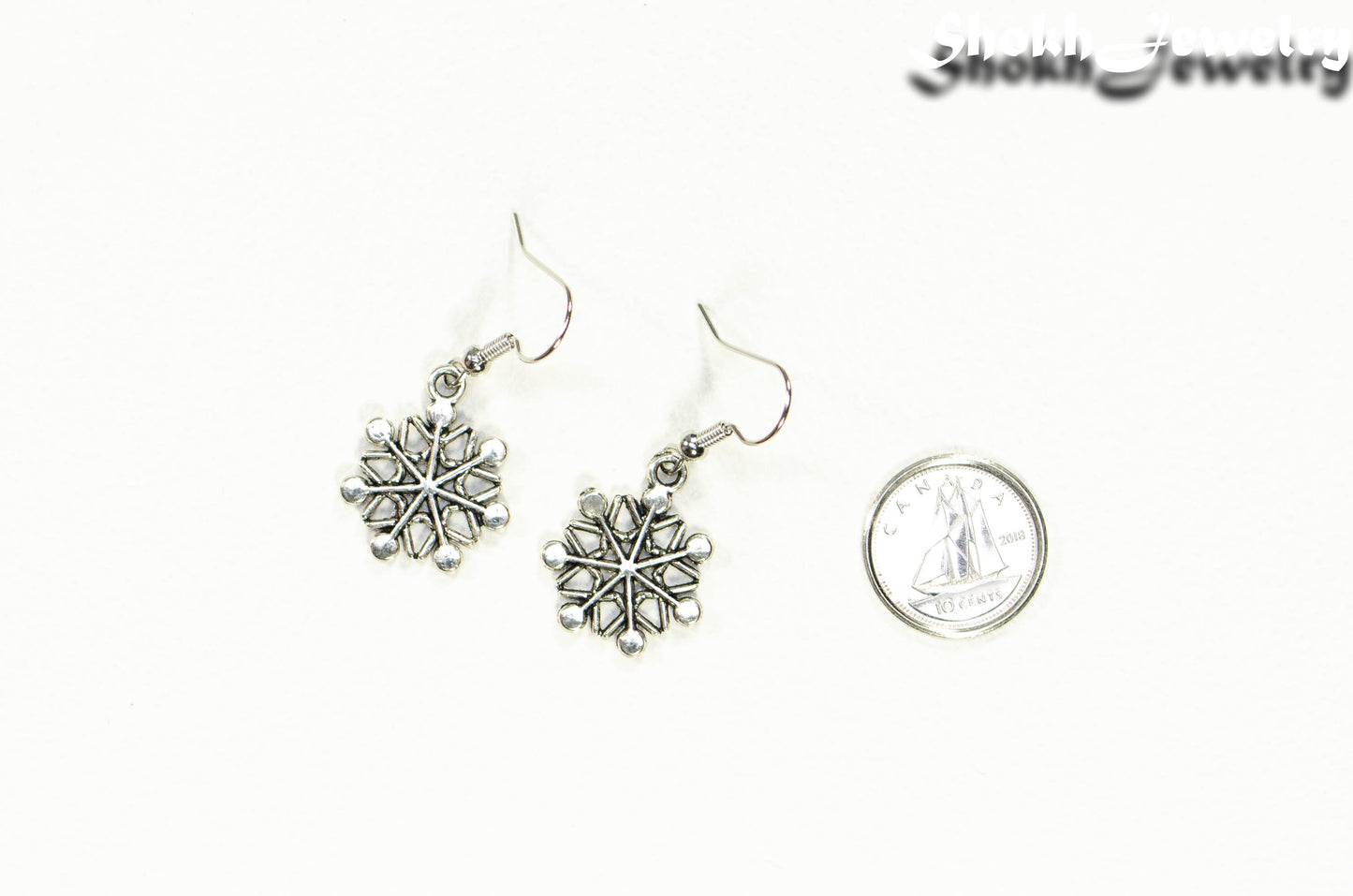 Christmas Snowflakes Charm Earrings beside a dime.