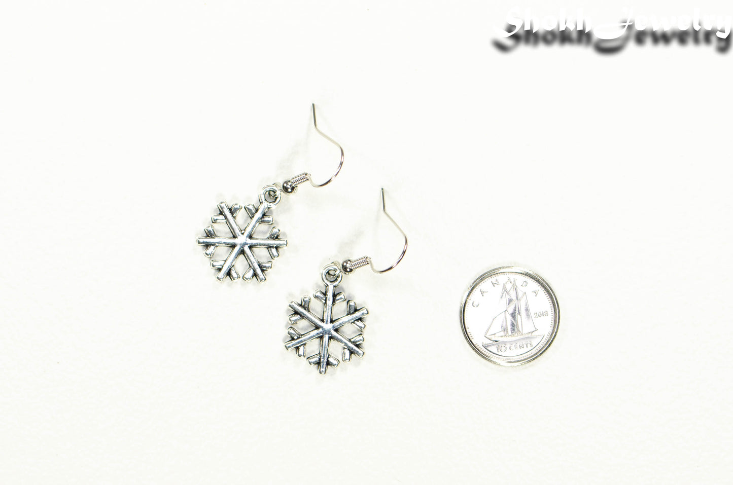 Christmas Snowflakes Charm Earrings beside a dime.