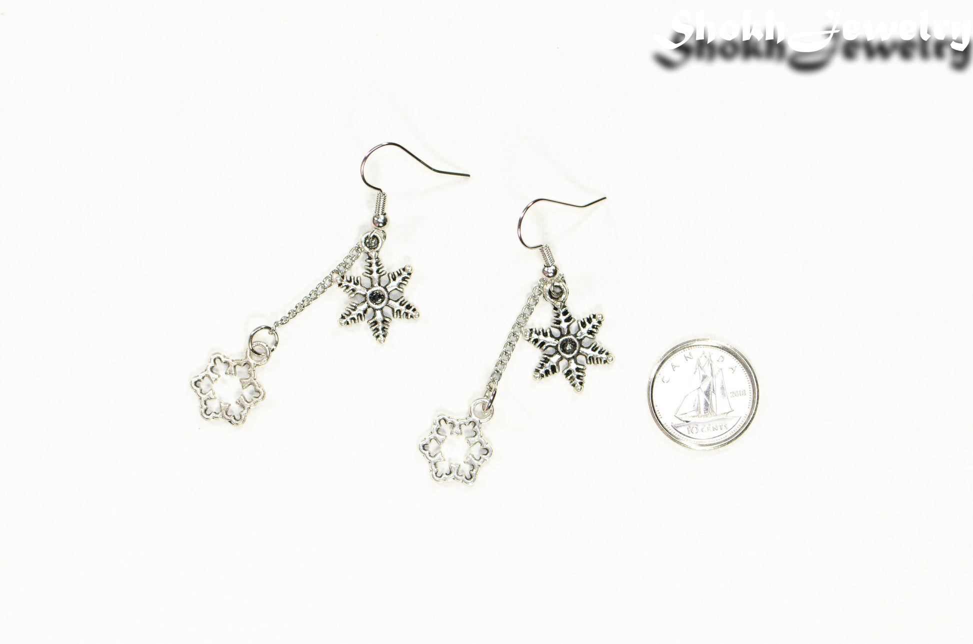 Long Chain and Snowflakes Charm Earrings beside a dime.