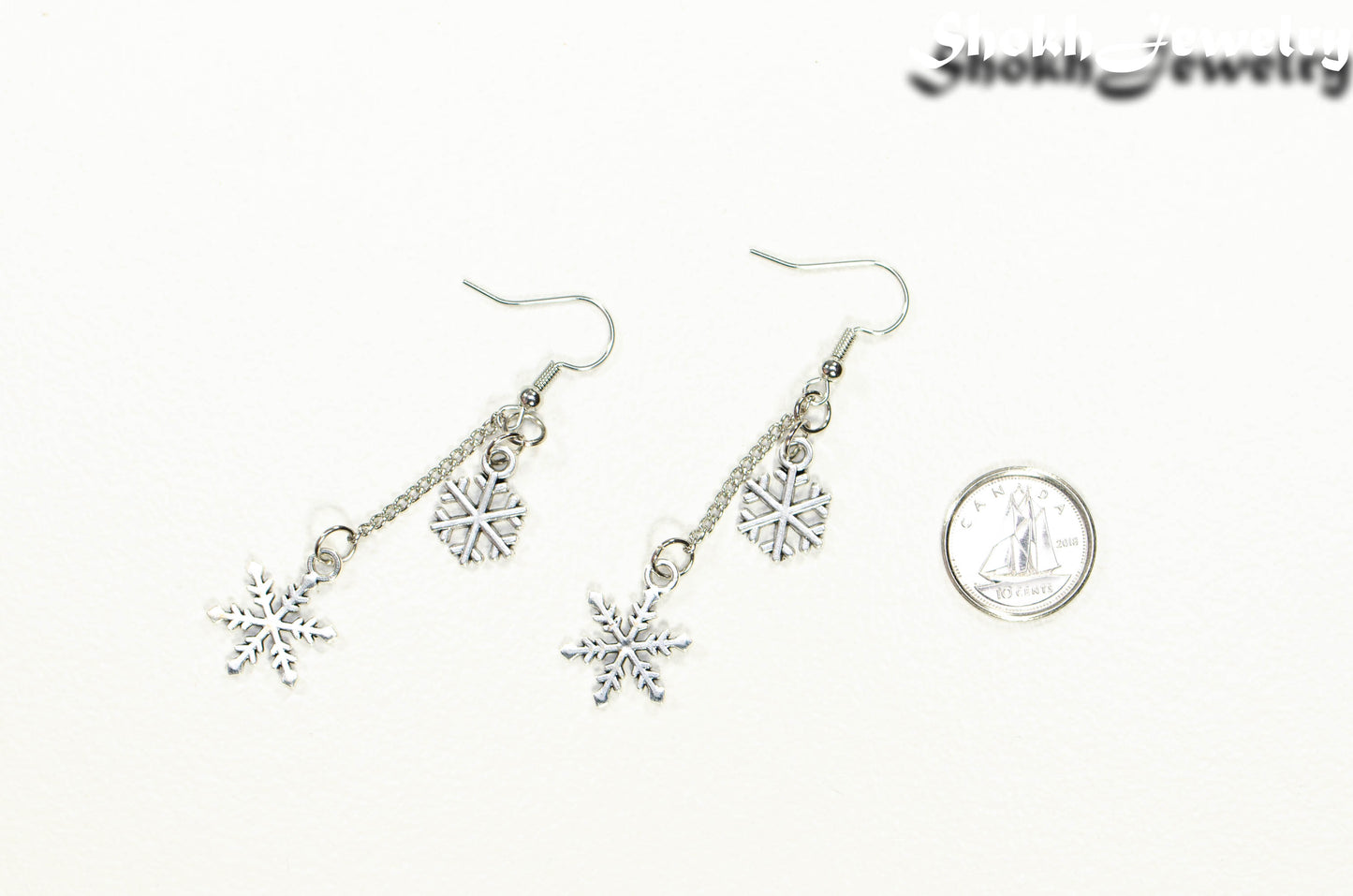 Long Chain and Snowflakes Charm Earrings beside a dime.