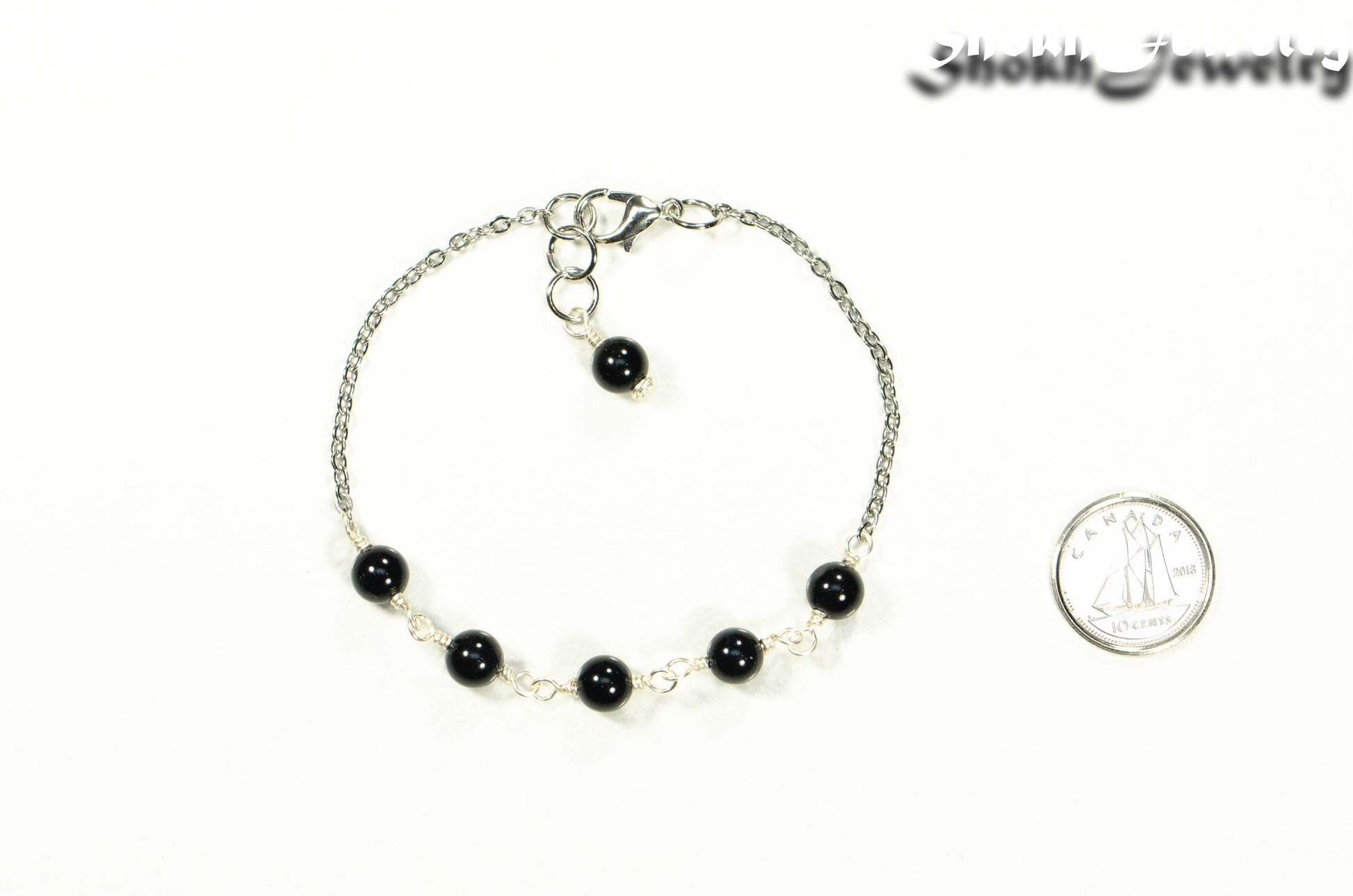 Black Obsidian and Stainless Steel Chain bracelet beside a dime.