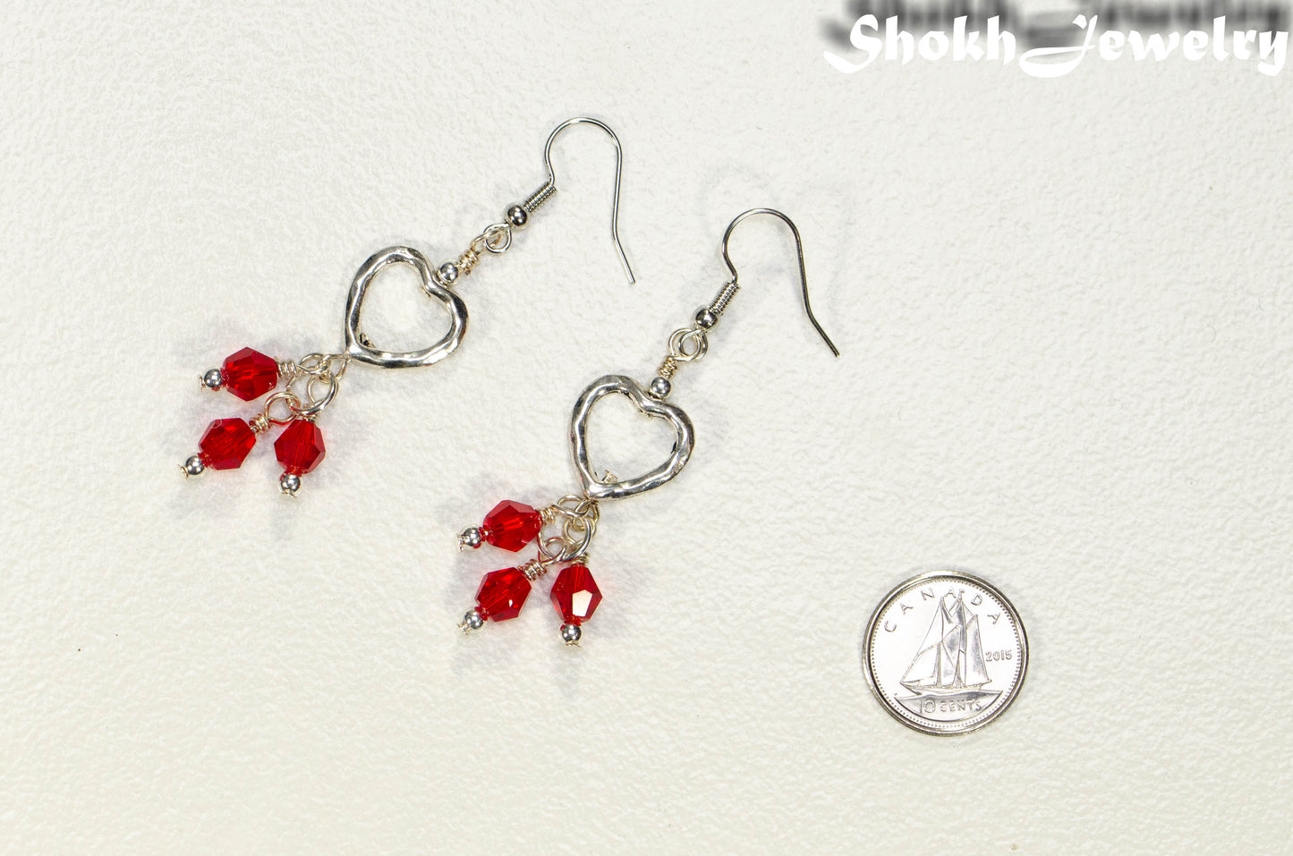 Silver Plated Heart and Red Glass Crystal Cluster Earrings beside a dime.