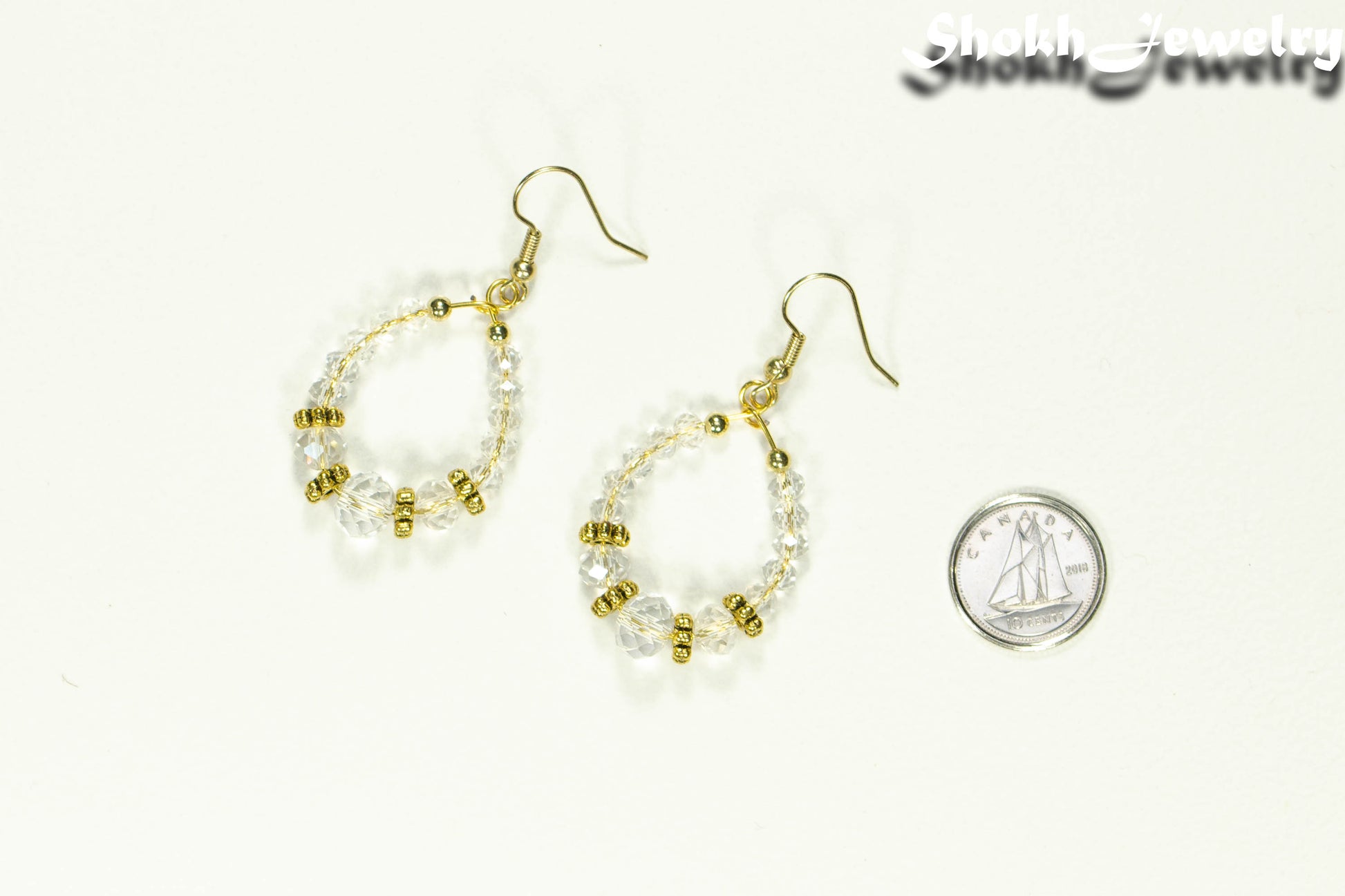 Clear Glass Crystal and Gold Hoop Earrings beside a dime.