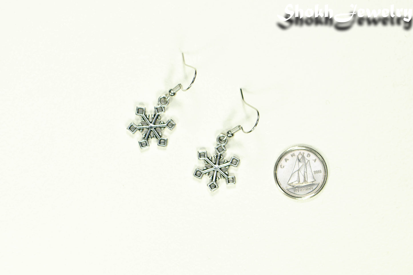 Christmas Snowflakes Charm Earrings beside a dime.