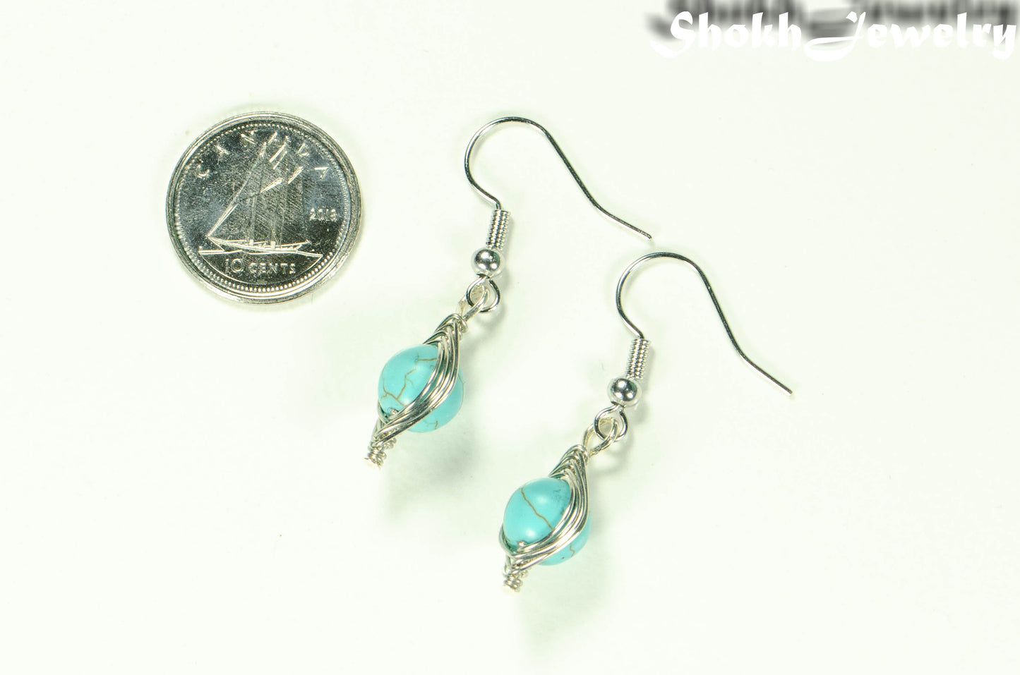 Turquoise Howlite Wire Wrapped Earrings beside a dime.