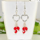 Silver Plated Heart and Red Glass Crystal Cluster Earrings displayed on a tea cup.