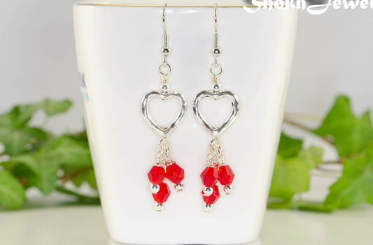 Silver Plated Heart and Red Glass Crystal Cluster Earrings displayed on a tea cup.