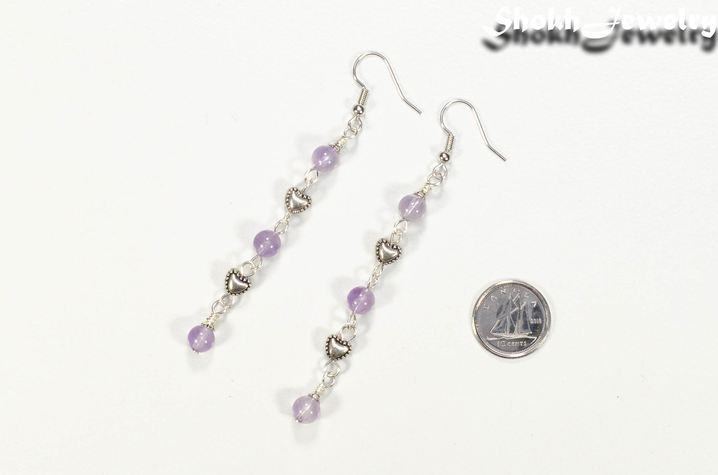 Long Amethyst and Heart Earrings beside a dime.