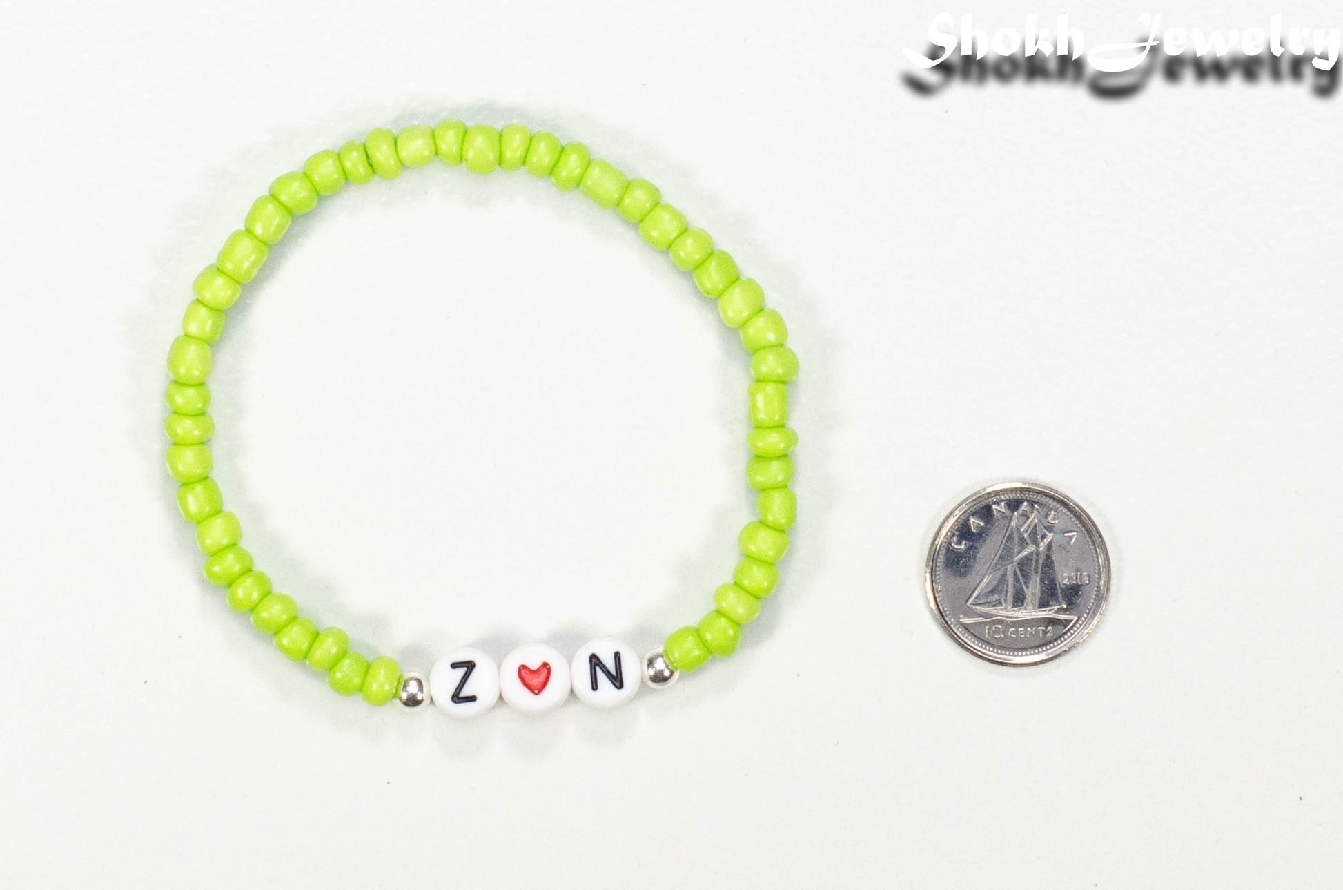 Lime Green Seed Beads Bracelet with Initials beside a dime.