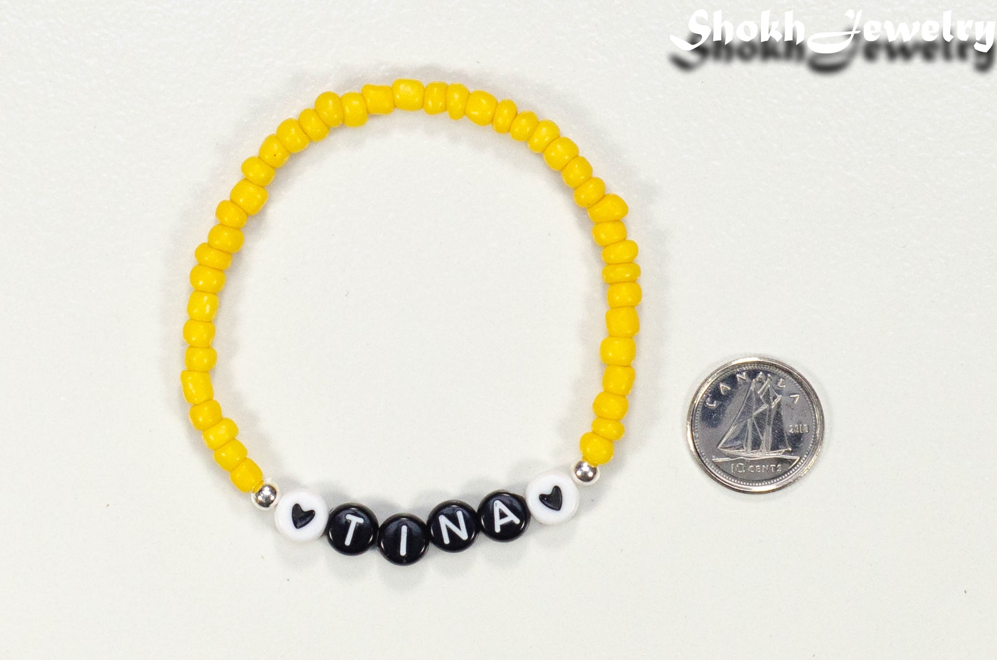 Yellow Seed Beads Name Bracelet beside a dime.