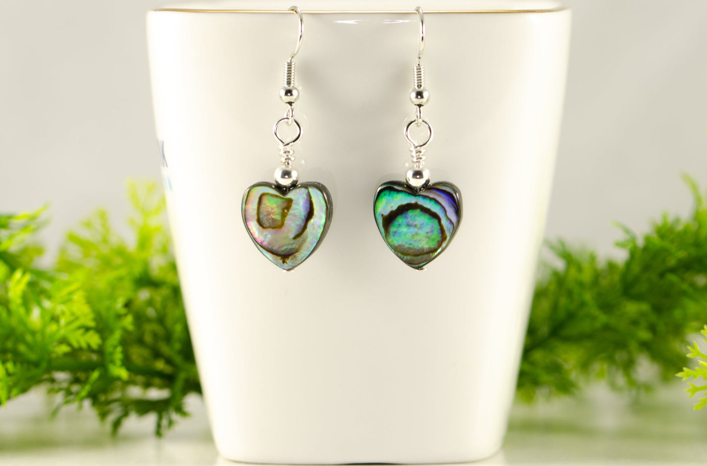 Heart Shaped Abalone Shell Earrings displayed on a tea cup.