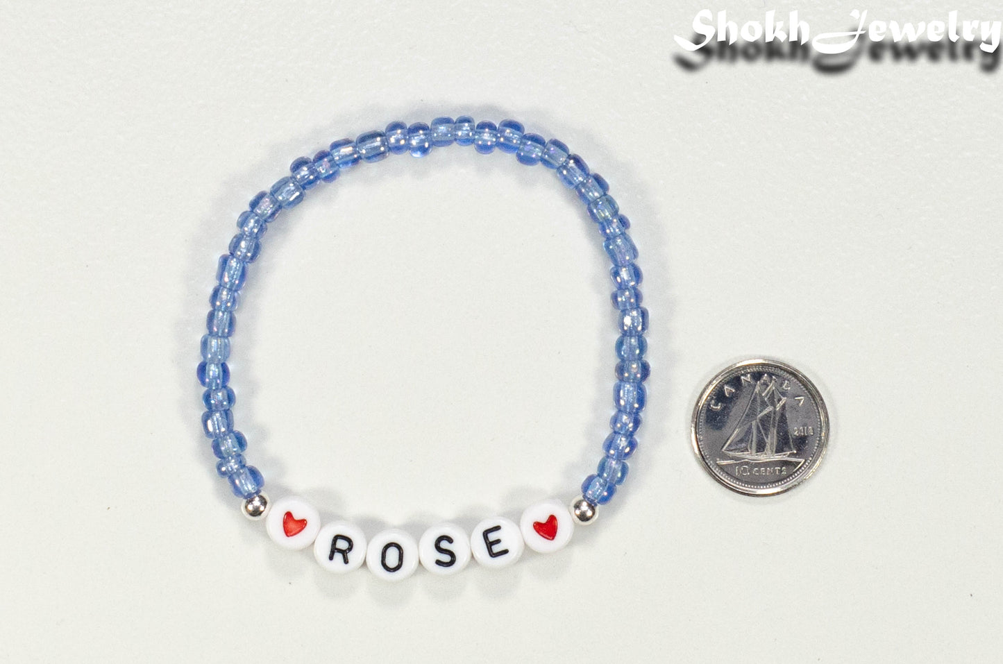 Blue Seed Beads Name Bracelet beside a dime.