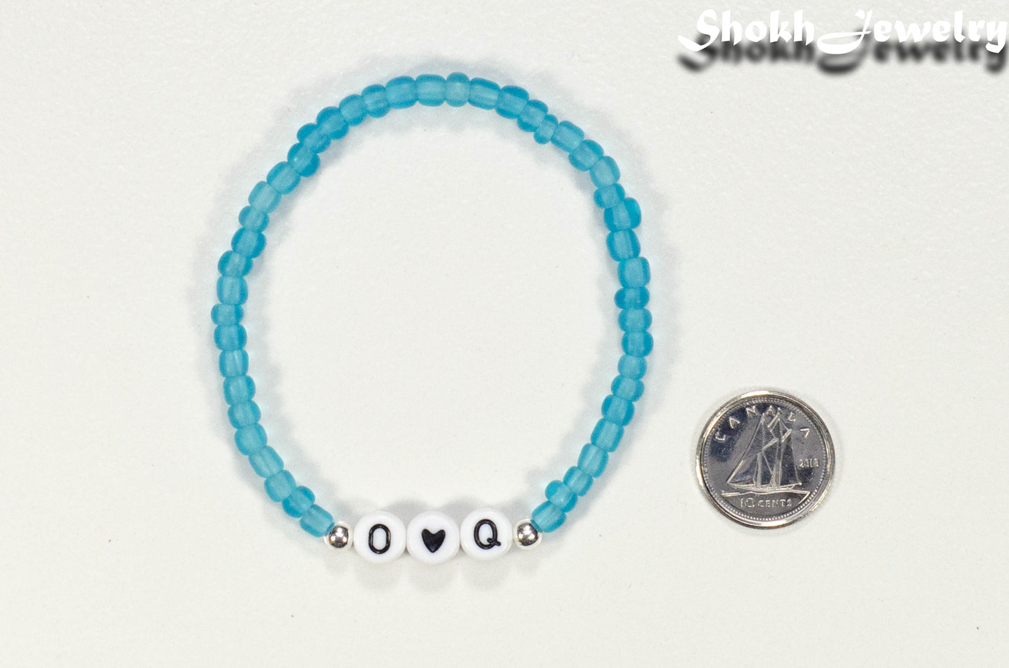 Blue seed beads Bracelet with Initials beside a dime.