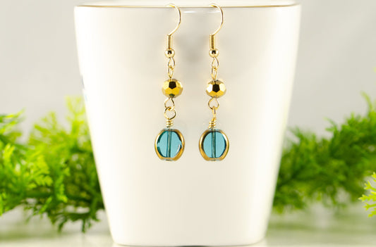 Teal and Gold Glass Bead Earrings displayed on a tea cup.