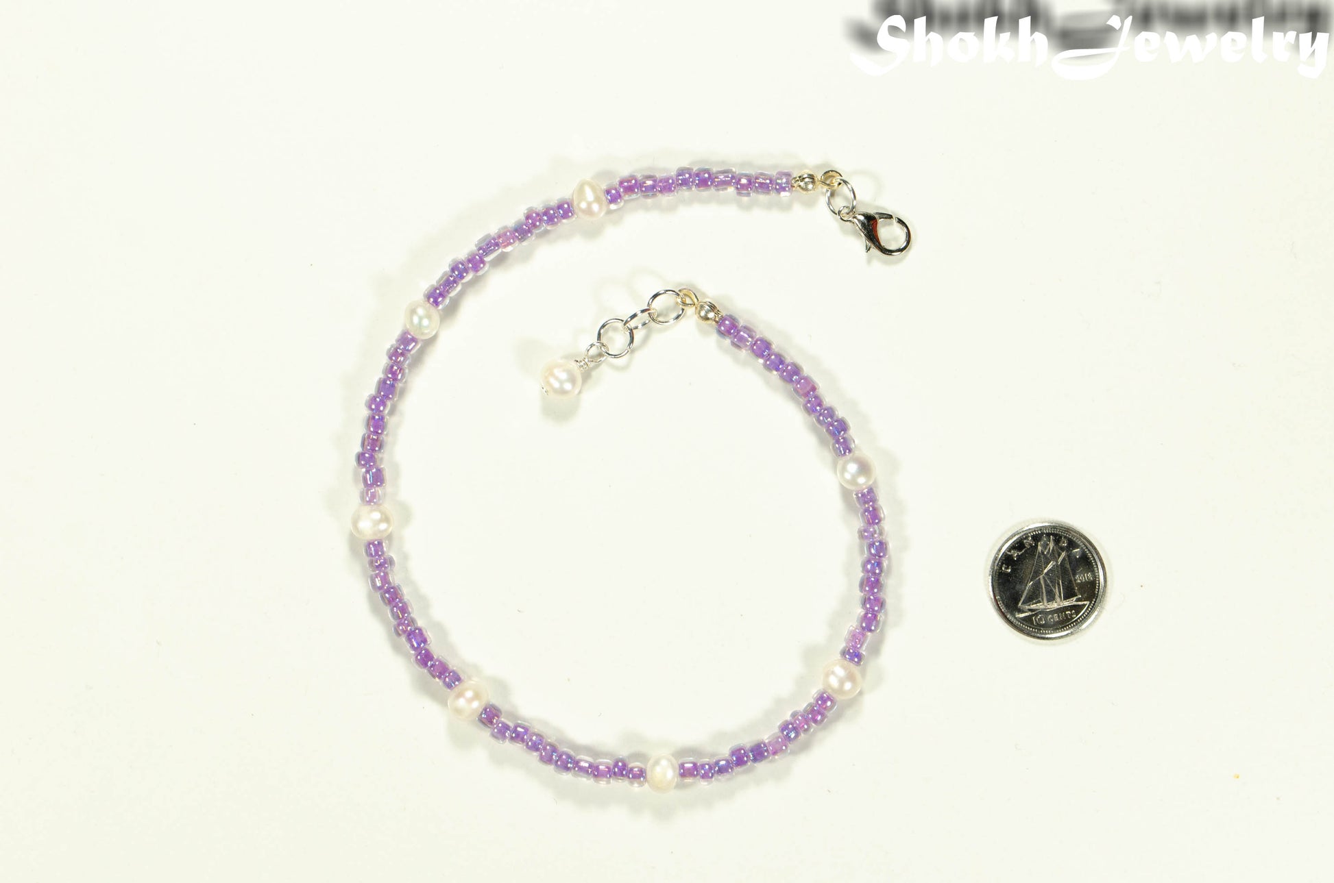 Freshwater Pearl and Purple Seed Bead Anklet beside a dime.
