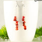 Long Silver Plated Chain and Red Coral Chip Earrings displayed on a coffee mug.