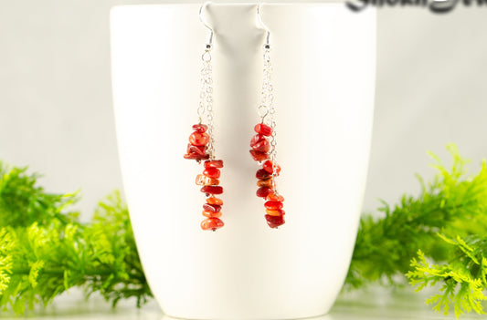 Long Silver Plated Chain and Red Coral Chip Earrings displayed on a coffee mug.