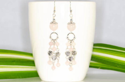 Statement Rose Quartz and Heart Chandelier Earrings displayed on a coffee mug.