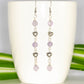 Long Amethyst and Heart Earrings displayed on a coffee mug.