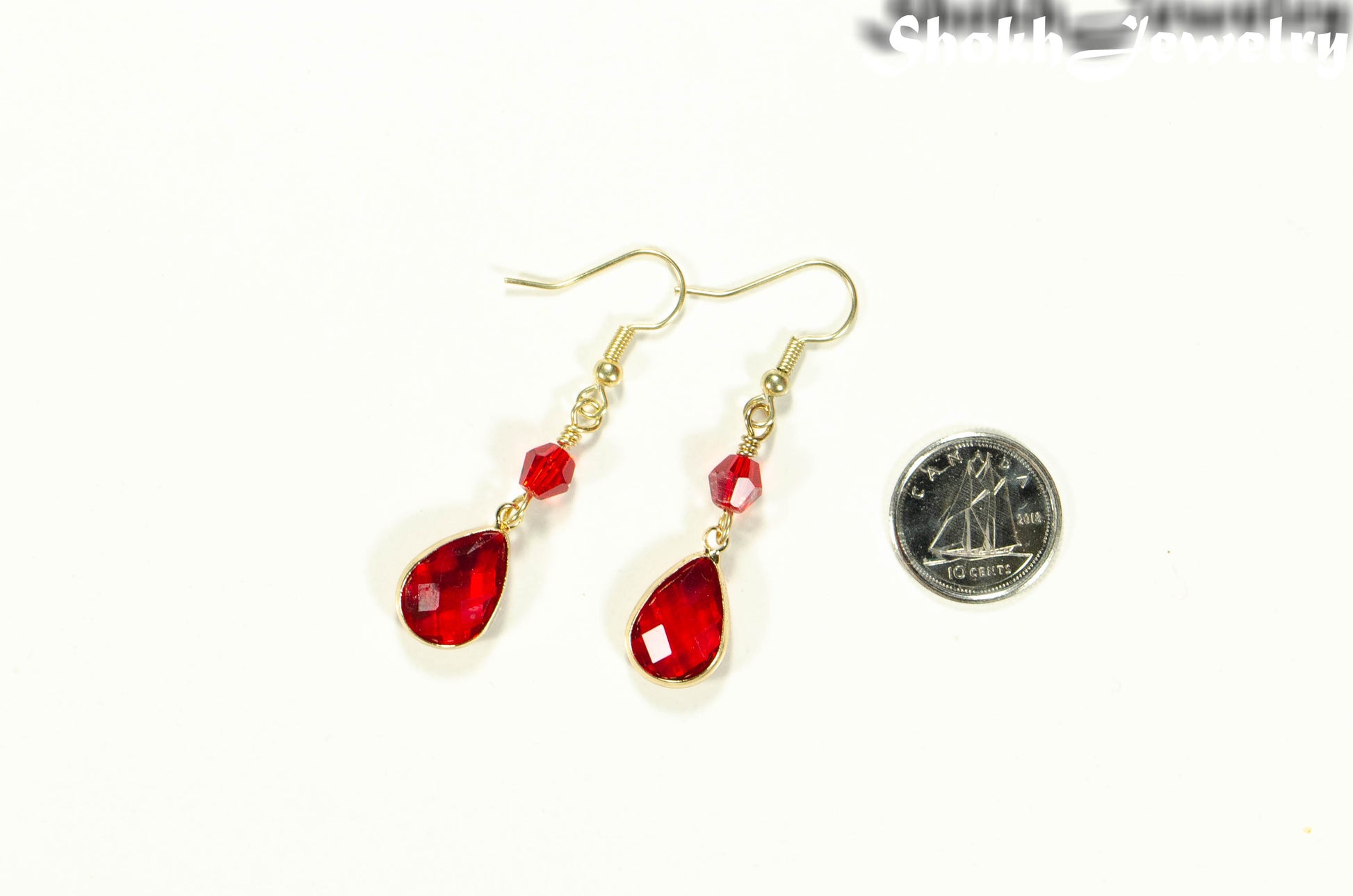 Red Glass Teardrop Dangle Earrings beside a dime.