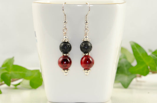Red Quartzite and Black Lava Rock Earrings displayed on a tea cup.