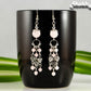 Statement Rose Quartz and Heart Chandelier Earrings displayed on a black coffee mug.