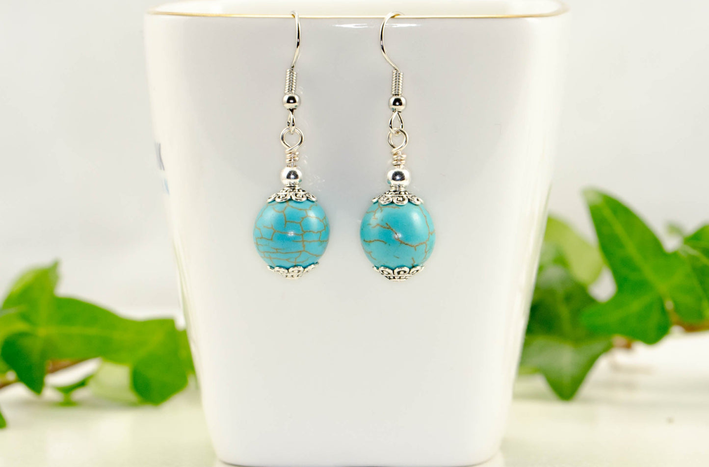 12mm Turquoise Howlite Dangle Earrings displayed on a tea cup.