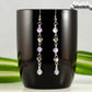 Long Amethyst and Heart Earrings displayed on a coffee mug.