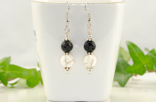 White Howlite and Black Lava Rock Earrings displayed on a tea cup.