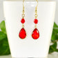 Red Glass Teardrop Dangle Earrings displayed on a tea cup.