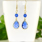 Blue Glass Teardrop Dangle Earrings displayed on a tea cup.