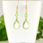 Green Glass Teardrop Dangle Earrings displayed on a tea cup.