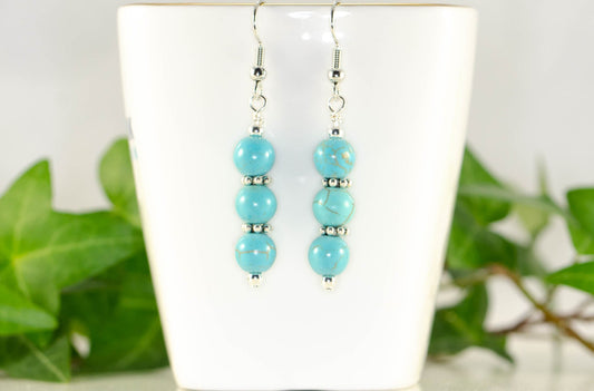 Turquoise Howlite Beaded Bar Earrings displayed on a tea cup.
