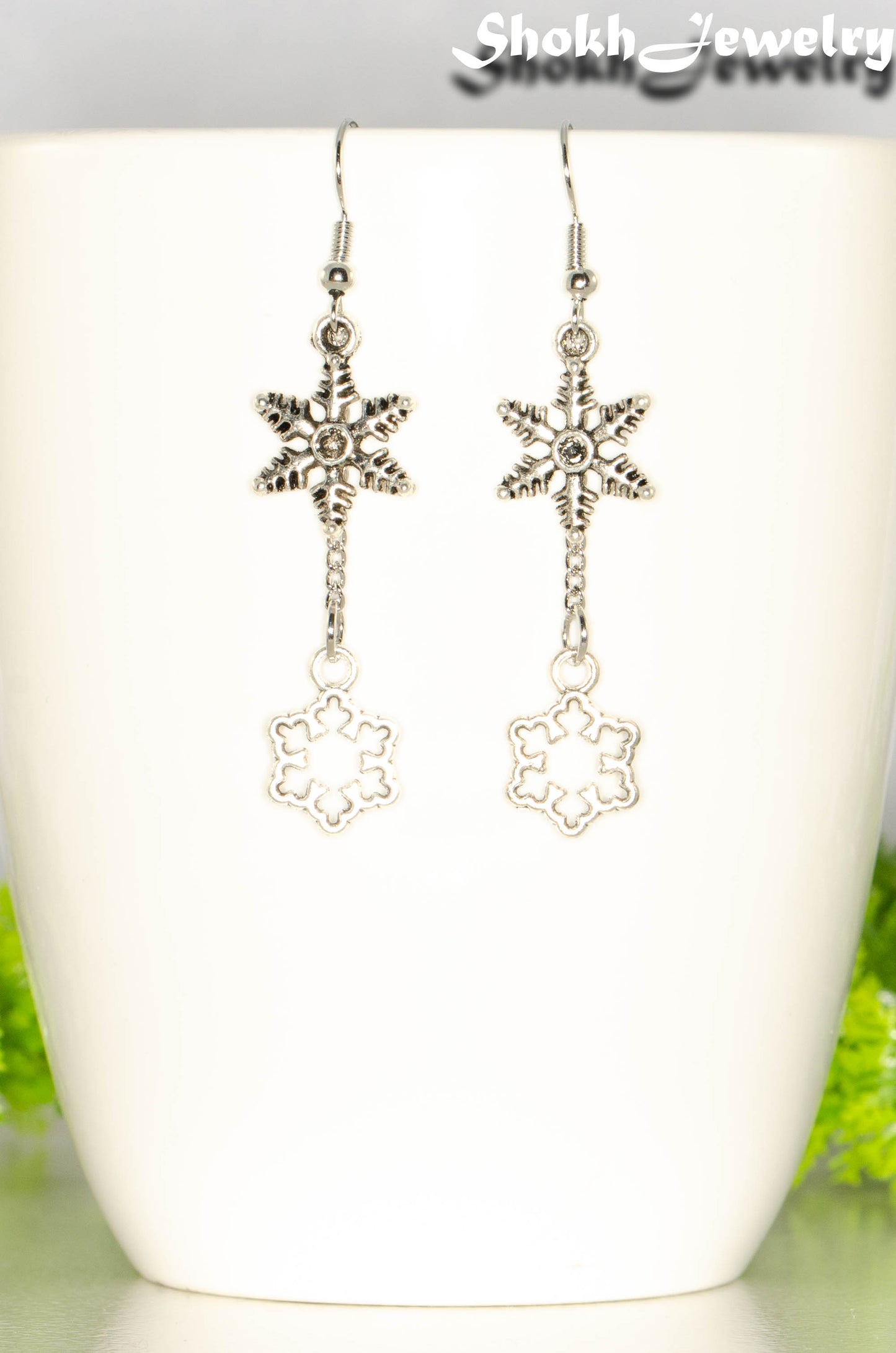 Long Chain and Snowflakes Charm Earrings displayed on a coffee mug.