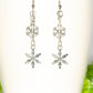 Long Chain and Snowflakes Charm Earrings displayed on a coffee mug.