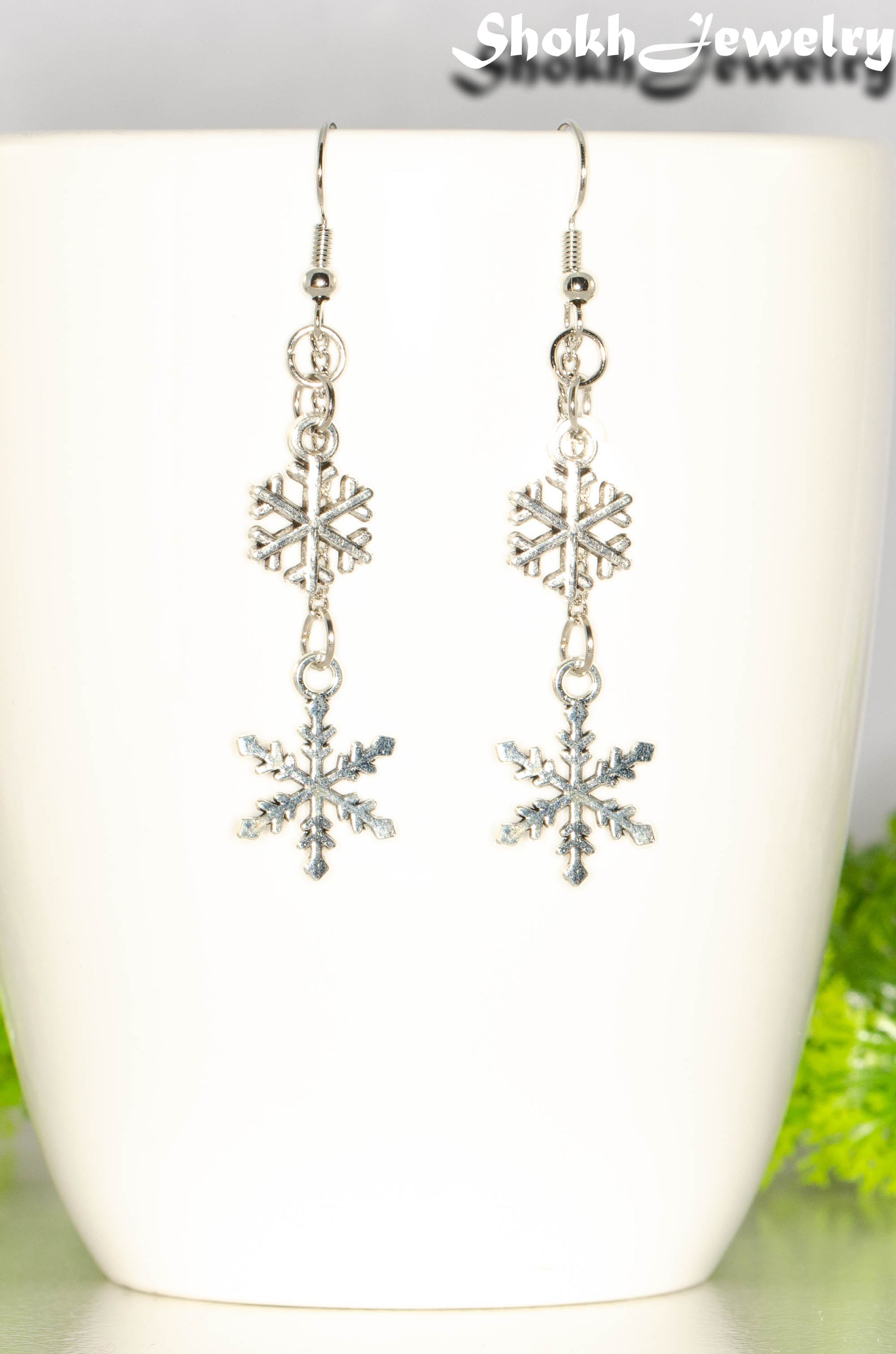 Long Chain and Snowflakes Charm Earrings displayed on a coffee mug.