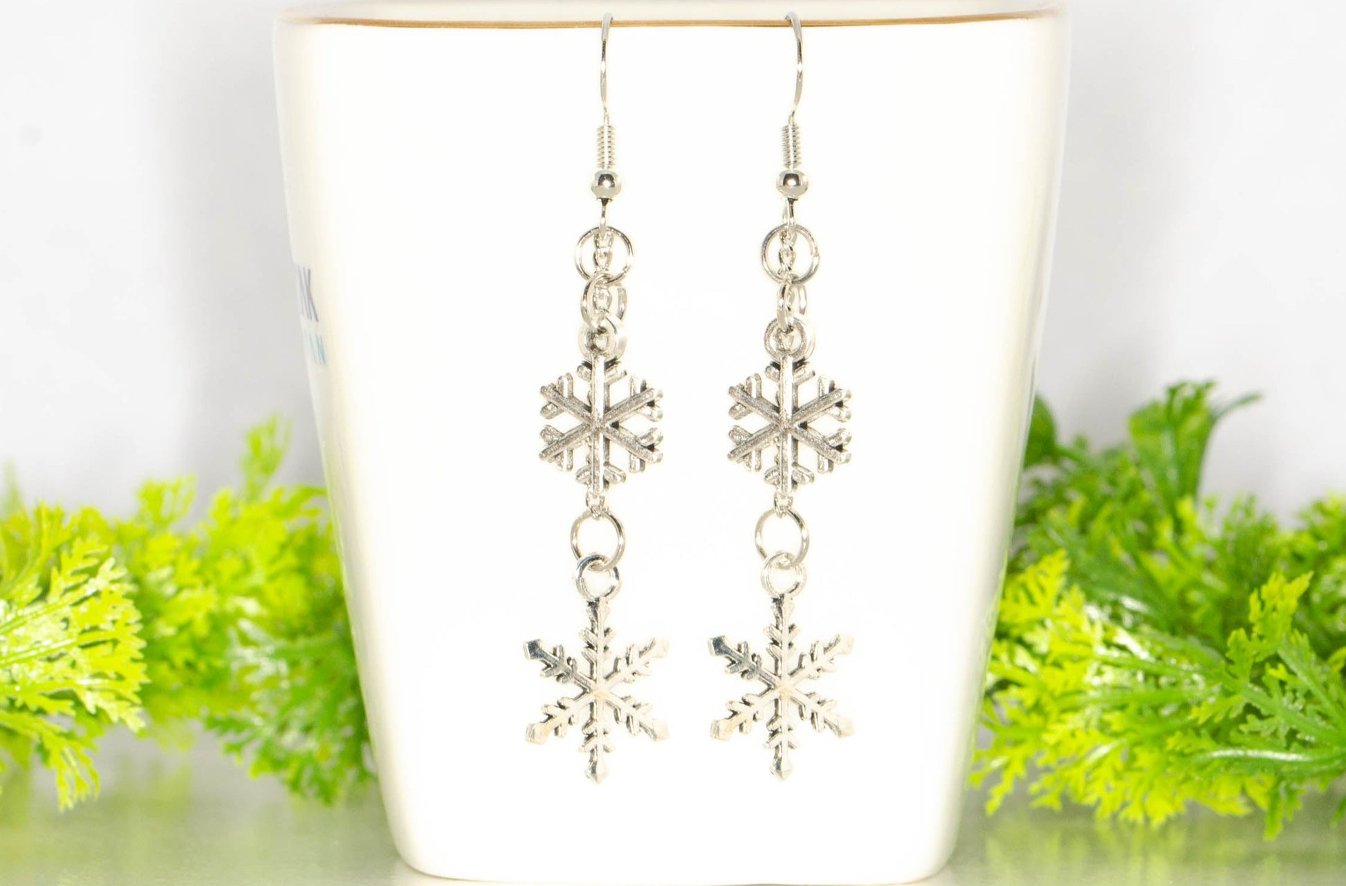 Long Chain and Snowflakes Charm Earrings displayed on a tea cup.