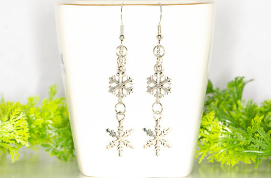 Long Chain and Snowflakes Charm Earrings displayed on a tea cup.